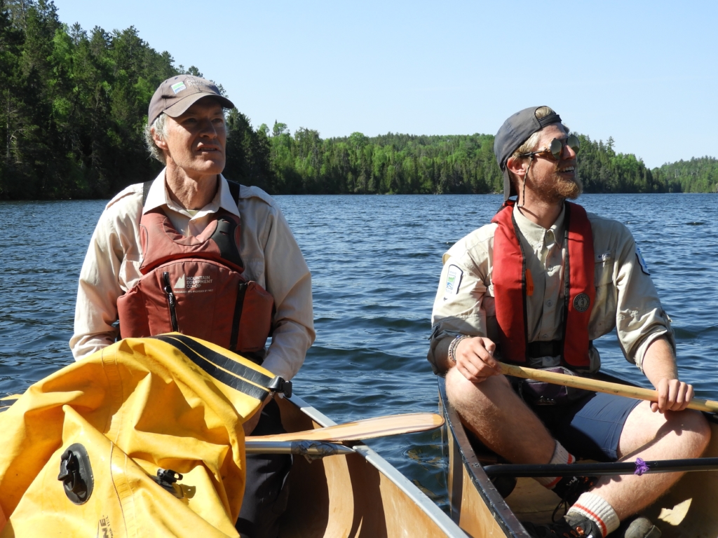 Brian Jackson (QPP Biologist) and Jared Walter Stachiw (QPP Assistant Biologist) surveying the shoreline of Kawnipi Lake for a stand of red pine to investigate for fire scars. Credit: Jill Legault.
