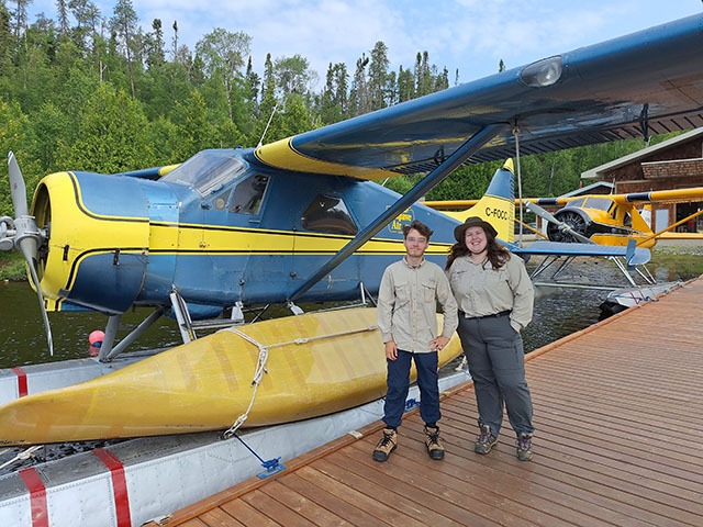 Students standing in front of floater plane wearing park uniforms.